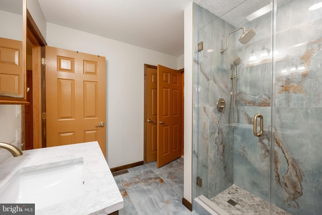 bathroom featuring vanity, a shower with door, and a textured ceiling