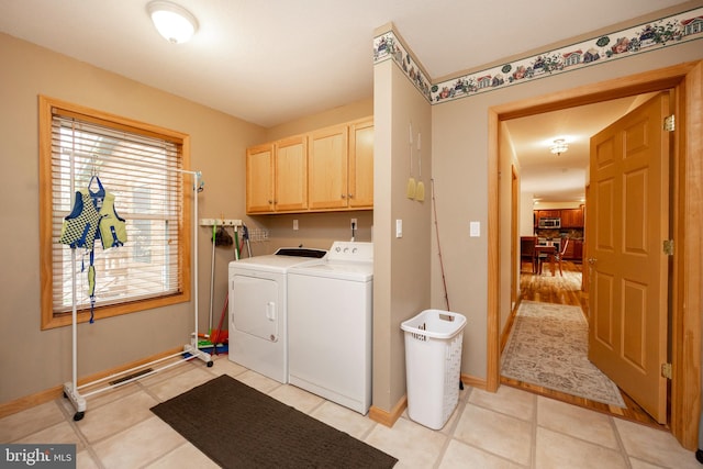 clothes washing area featuring light tile patterned flooring, cabinets, and independent washer and dryer