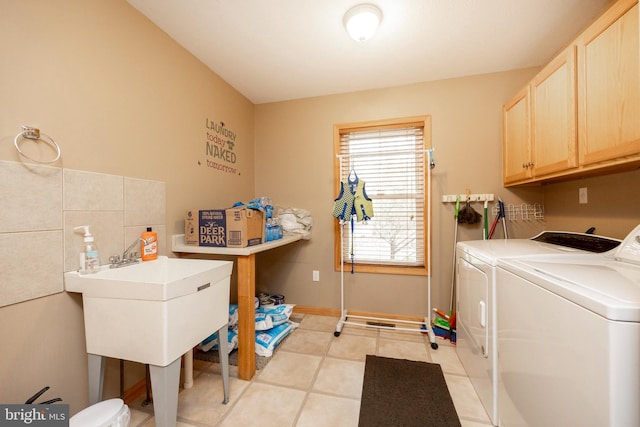 washroom with washer and clothes dryer, light tile patterned floors, and cabinets