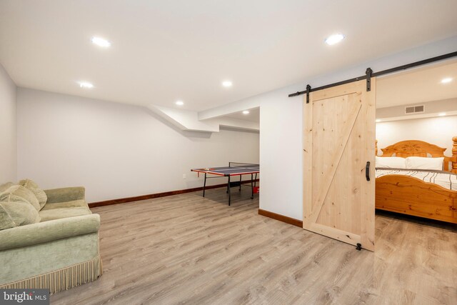 playroom featuring a barn door and light hardwood / wood-style floors