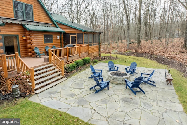 view of patio / terrace with a sunroom, a deck, and an outdoor fire pit