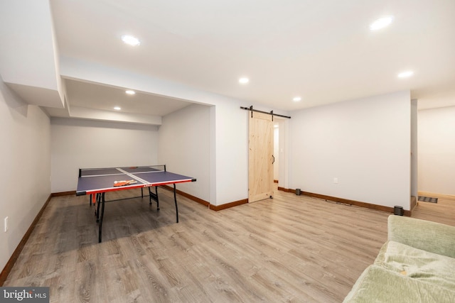 playroom with a barn door and light hardwood / wood-style flooring