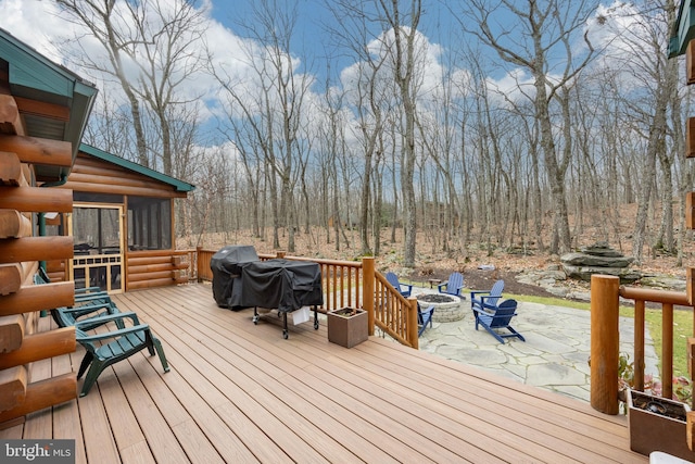 wooden deck featuring a sunroom and an outdoor fire pit