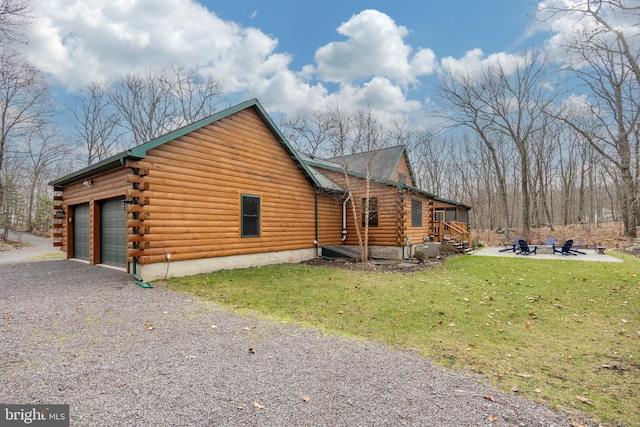 view of side of home featuring a lawn, a fire pit, and a garage