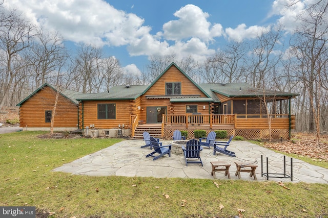 rear view of house with a sunroom, a yard, a fire pit, a deck, and a patio area