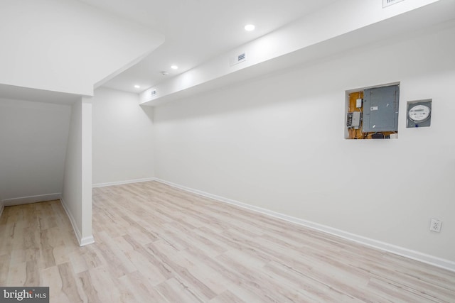 basement featuring light wood-type flooring and electric panel