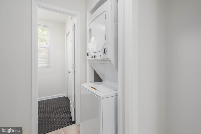 laundry area with stacked washing maching and dryer and light hardwood / wood-style flooring