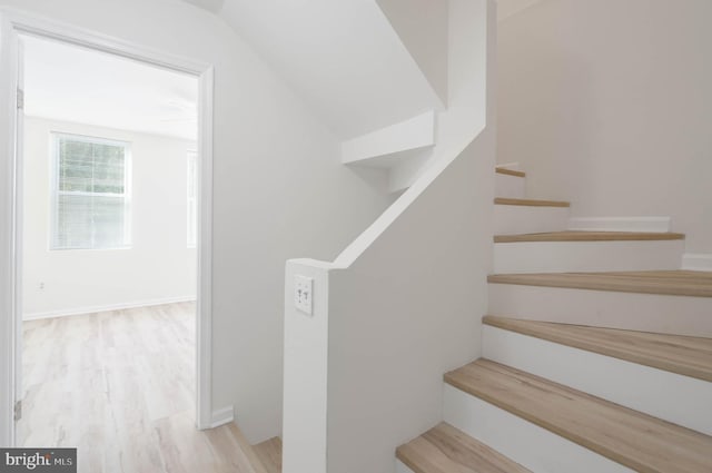 stairs featuring hardwood / wood-style floors and lofted ceiling