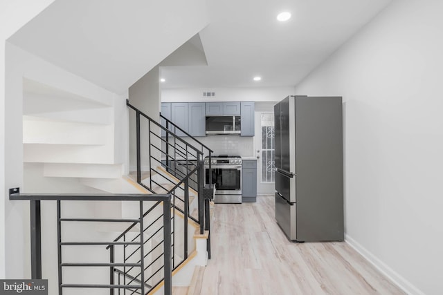 kitchen with tasteful backsplash, gray cabinetry, stainless steel appliances, and light wood-type flooring