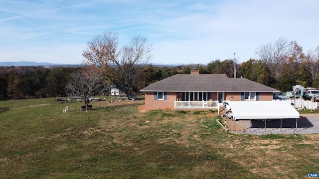 back of house featuring a yard, a porch, and a carport