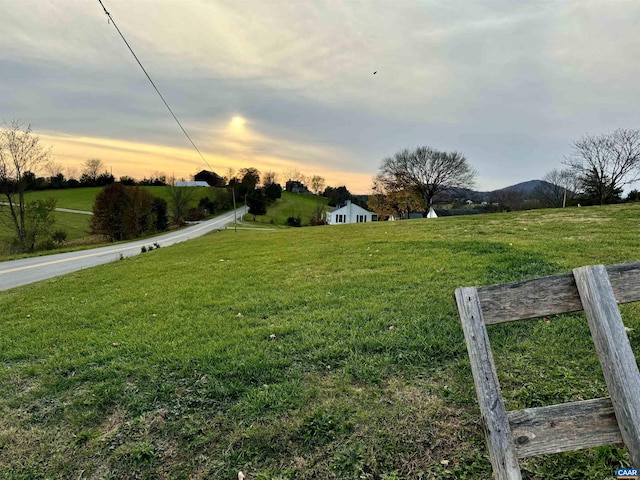 yard at dusk featuring a rural view