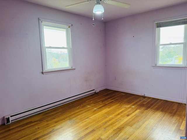 empty room with ceiling fan, wood-type flooring, and a baseboard heating unit