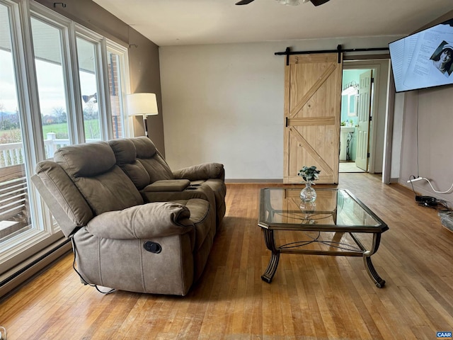 living room with hardwood / wood-style flooring, ceiling fan, a barn door, and baseboard heating