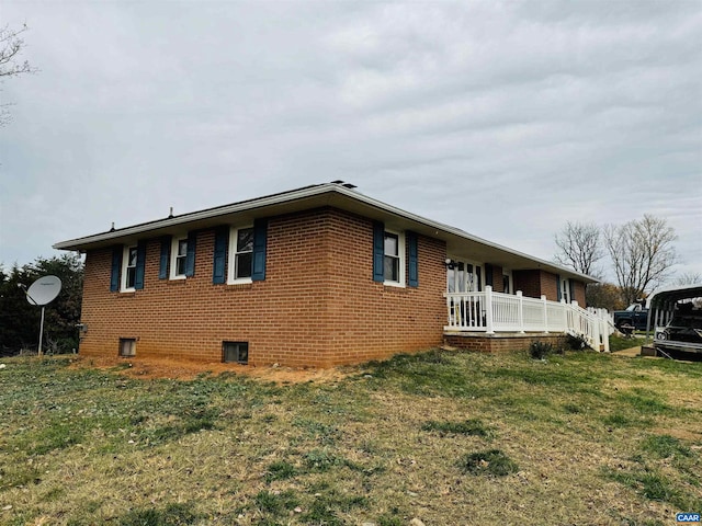 view of side of property with a lawn and covered porch