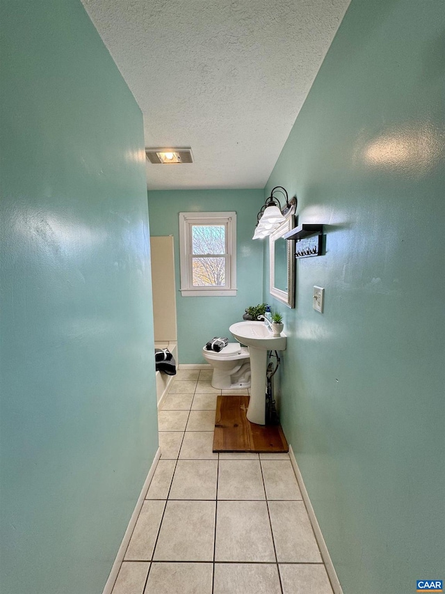 bathroom featuring tile patterned flooring, sink, toilet, and a textured ceiling