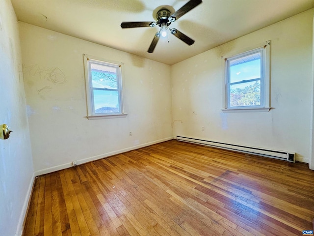 empty room featuring baseboard heating, ceiling fan, and light hardwood / wood-style flooring