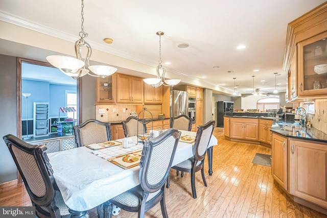 dining room featuring crown molding, sink, and light hardwood / wood-style floors