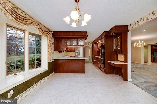 kitchen featuring stainless steel refrigerator with ice dispenser, a notable chandelier, double oven, kitchen peninsula, and decorative light fixtures