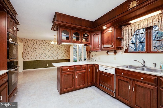 kitchen featuring dishwasher, pendant lighting, kitchen peninsula, and sink