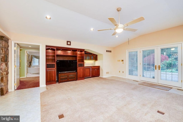 unfurnished living room featuring ceiling fan, light colored carpet, french doors, and vaulted ceiling