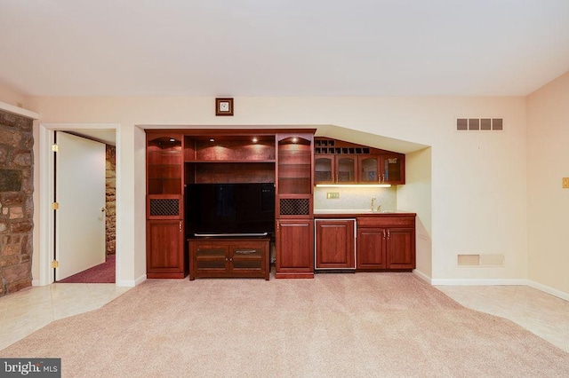 unfurnished living room featuring wet bar and light carpet