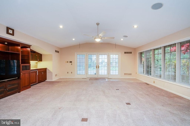 unfurnished living room featuring french doors, light colored carpet, vaulted ceiling, and ceiling fan