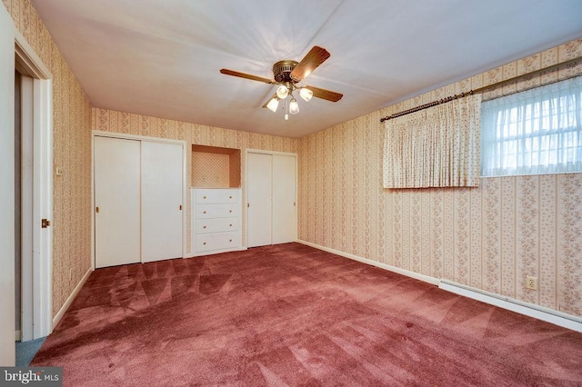 unfurnished bedroom featuring carpet flooring, baseboard heating, ceiling fan, and multiple closets