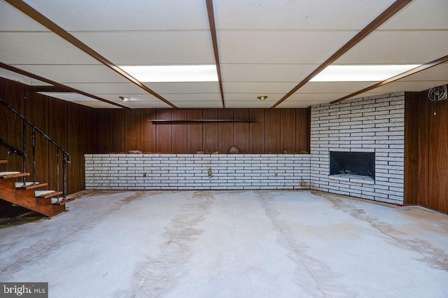 basement with wood walls and a brick fireplace