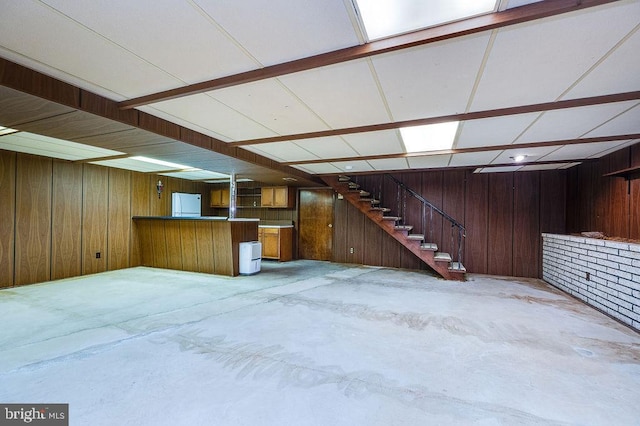 basement with wooden walls and white fridge