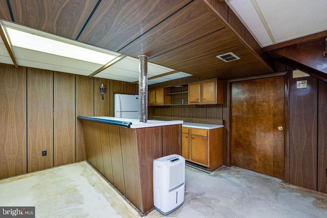 kitchen featuring kitchen peninsula, white refrigerator, and wood walls