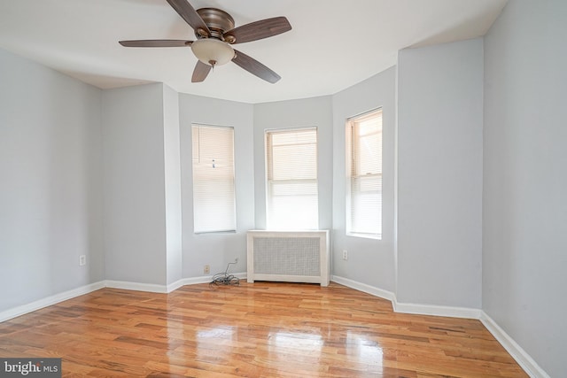 empty room with radiator heating unit, light wood-type flooring, and ceiling fan