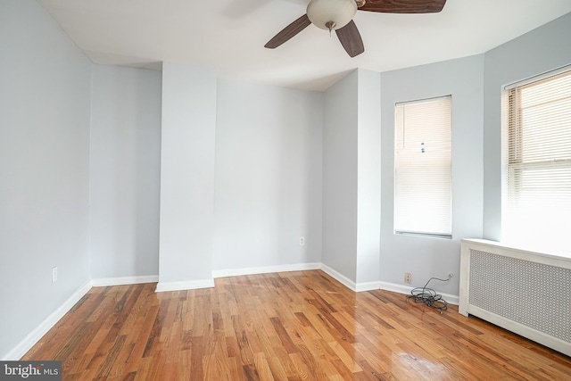 spare room featuring radiator heating unit, light hardwood / wood-style flooring, and ceiling fan