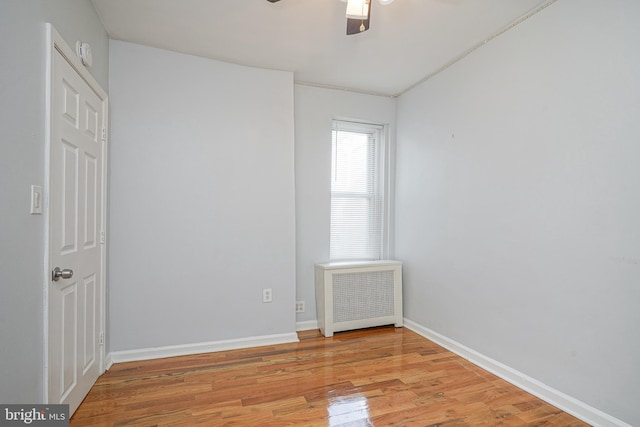 spare room featuring ceiling fan, radiator heating unit, and light hardwood / wood-style floors