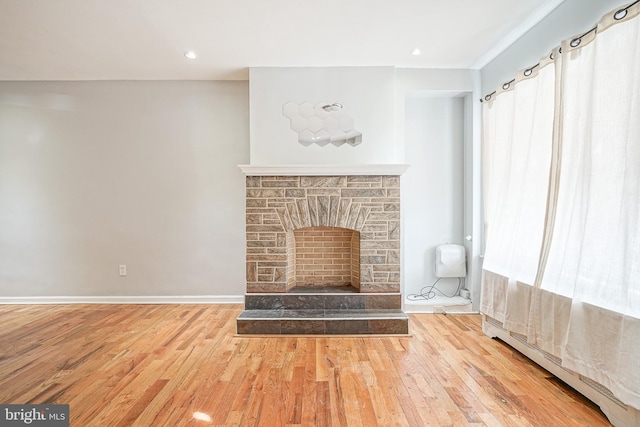 unfurnished living room featuring a fireplace, light hardwood / wood-style flooring, and a baseboard radiator