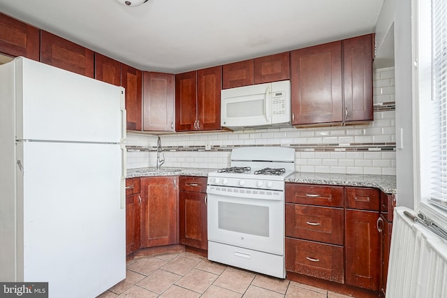 kitchen featuring radiator heating unit, sink, light stone counters, backsplash, and white appliances