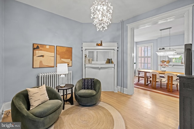 living area with hardwood / wood-style floors, a notable chandelier, and radiator