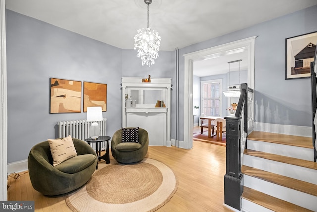 living area featuring a chandelier, light wood-type flooring, and radiator