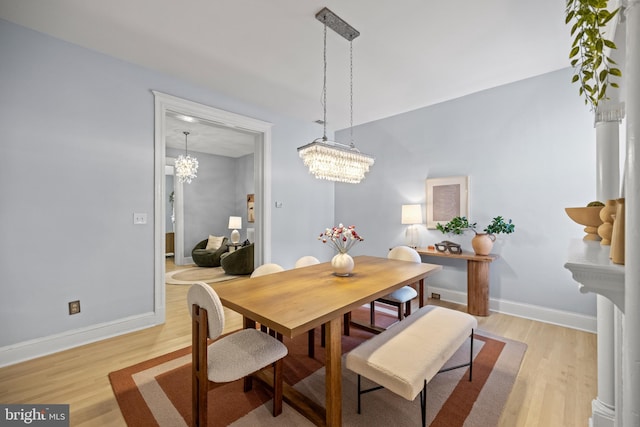 dining space featuring light hardwood / wood-style floors and a notable chandelier