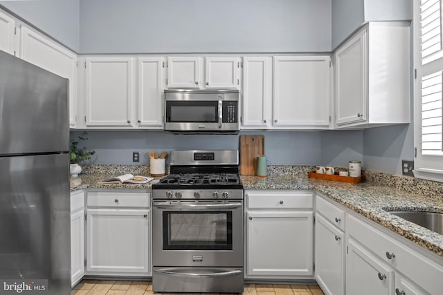 kitchen featuring white cabinetry, light stone countertops, and appliances with stainless steel finishes