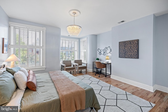 bedroom with light hardwood / wood-style flooring and an inviting chandelier