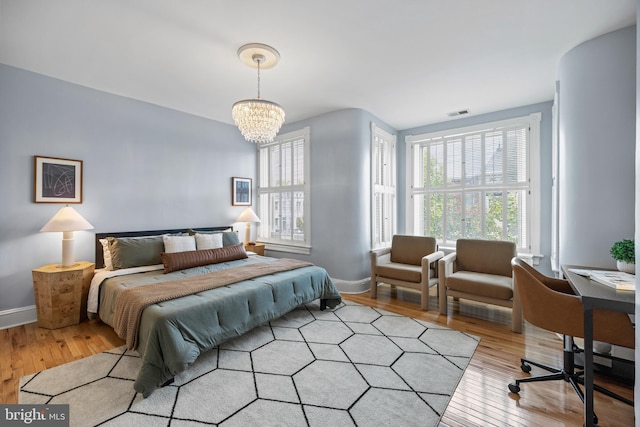 bedroom with a chandelier and light wood-type flooring