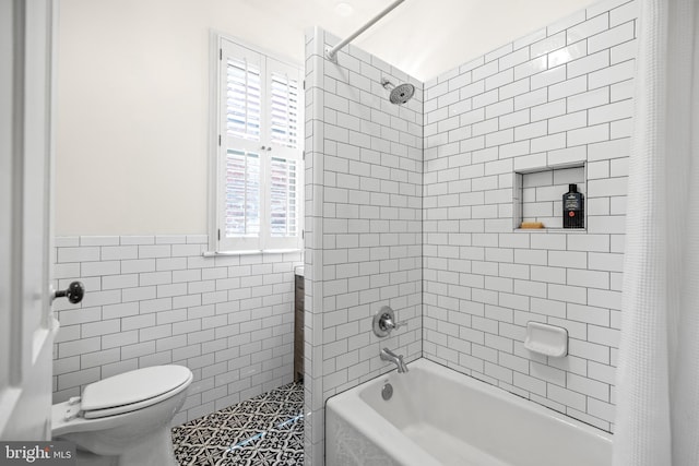 bathroom featuring shower / tub combo, toilet, and tile walls