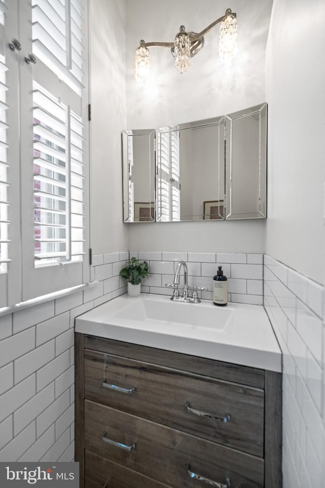 bathroom with a wealth of natural light, vanity, and tile walls