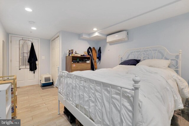 bedroom with light hardwood / wood-style floors, a wall unit AC, and a closet