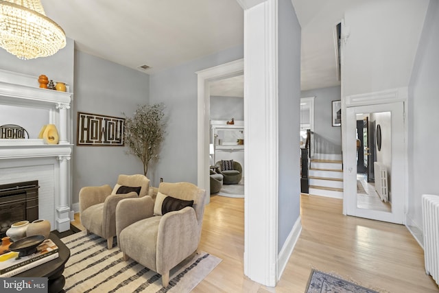 living room featuring light wood-type flooring, radiator, and a notable chandelier