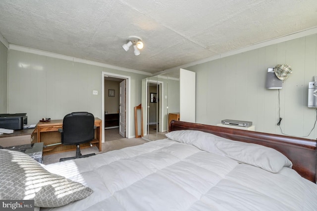 bedroom featuring a walk in closet, a textured ceiling, wooden walls, crown molding, and a closet