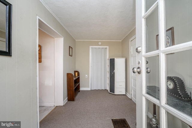 corridor featuring light carpet, a textured ceiling, and crown molding