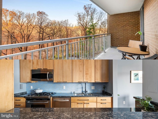 kitchen featuring brick wall, dark stone countertops, sink, and appliances with stainless steel finishes