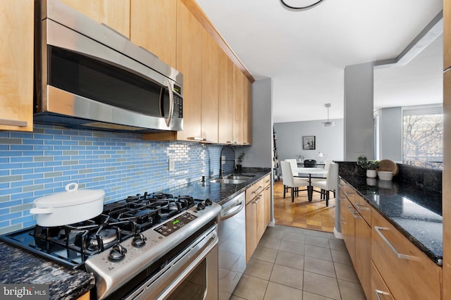 kitchen with sink, stainless steel appliances, dark stone counters, and tasteful backsplash