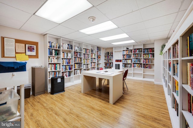 office space featuring a drop ceiling, light hardwood / wood-style floors, and built in shelves